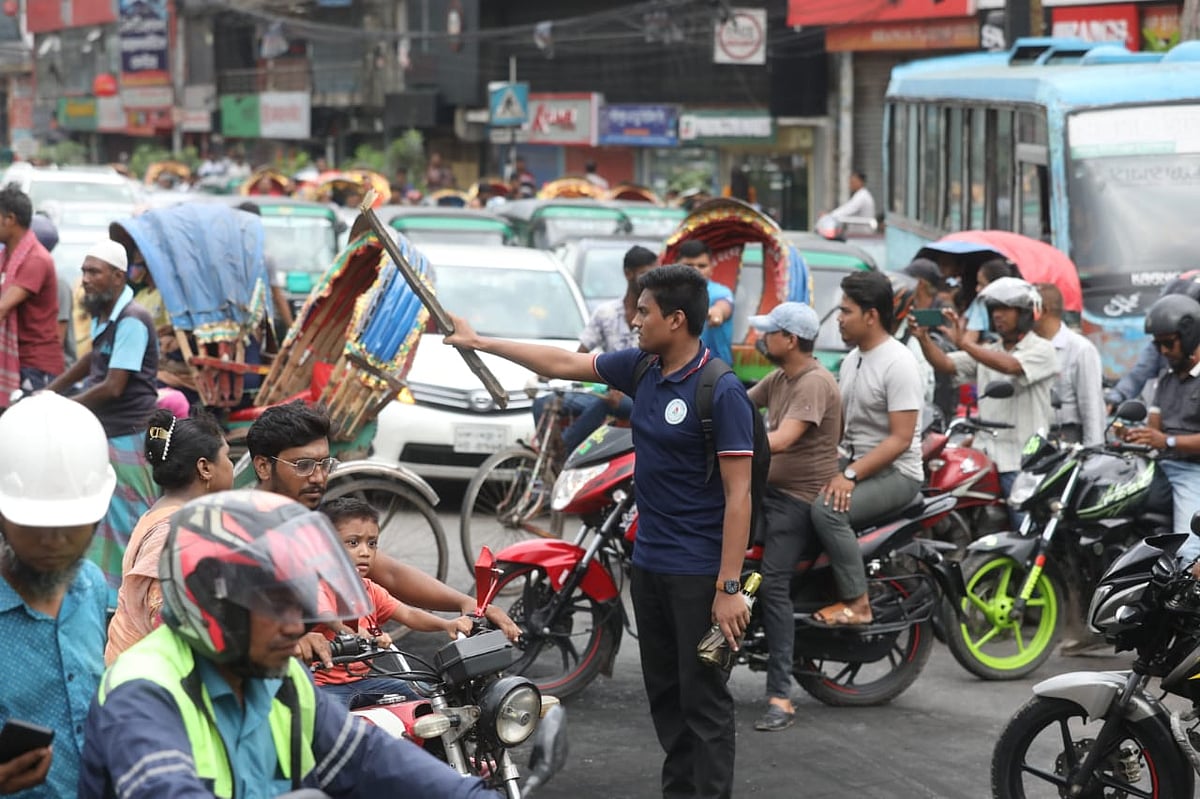 রাজধানীর আসাদগেটে ট্রাফিক নিয়ন্ত্রণ করছেন এক  শিক্ষার্থী। আজ মঙ্গলবার দুপুরে।